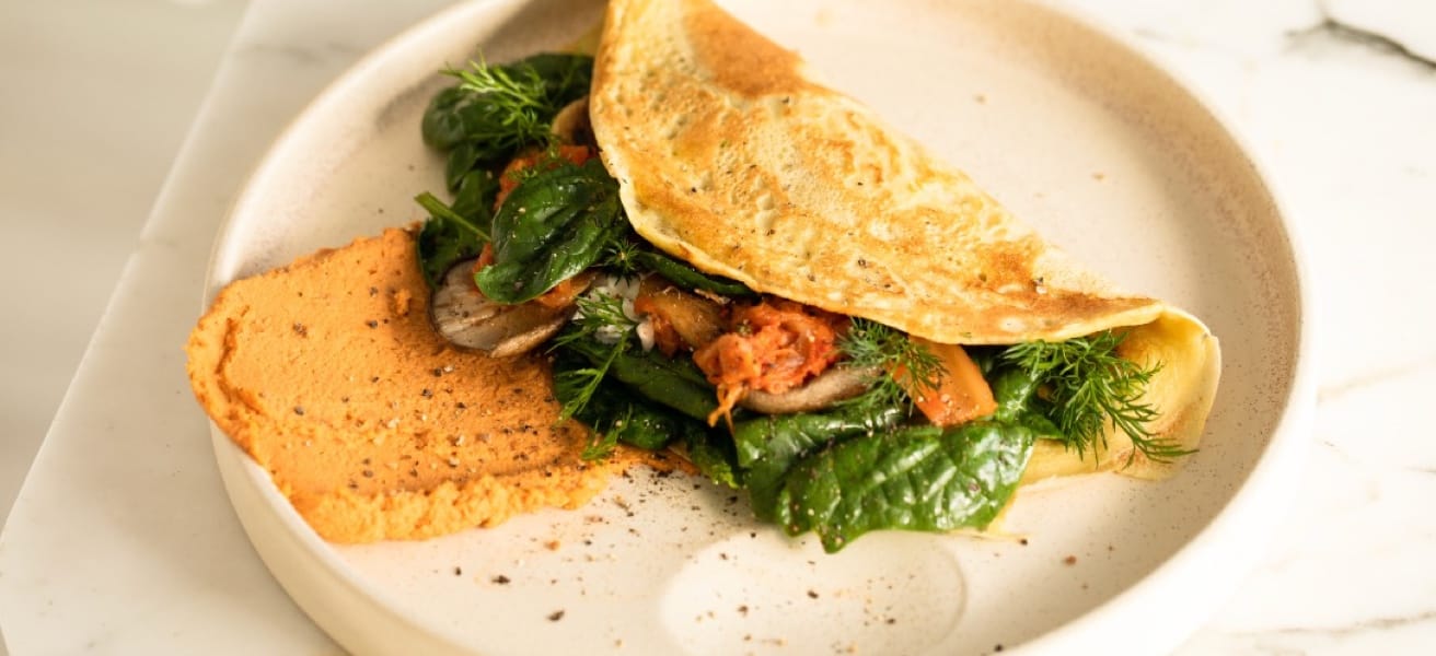 Image of an omelette with green veggies and herbs